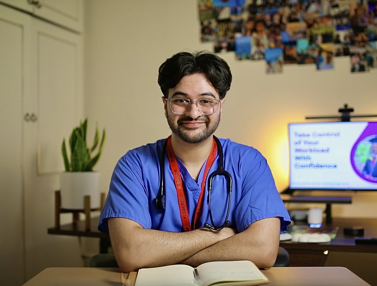 Dr Waleed Ahmad, NHS doctor and founder of A-Level Accelerators, at his desk in scrubs